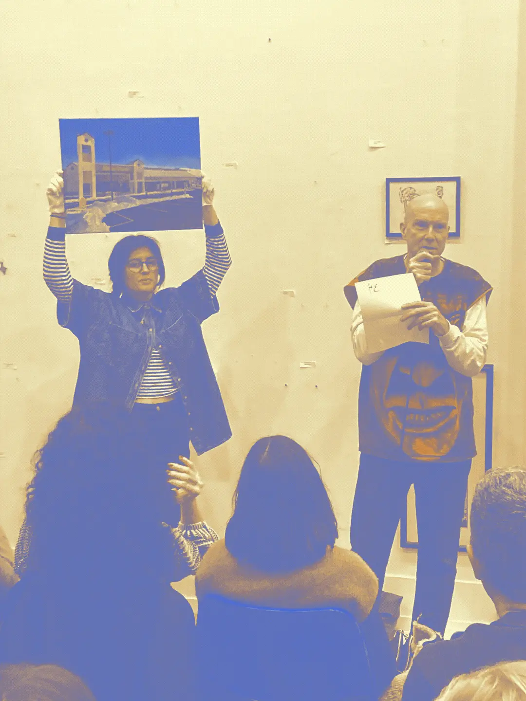 someone holding up a painting and an auctioneer spotting bids in audience