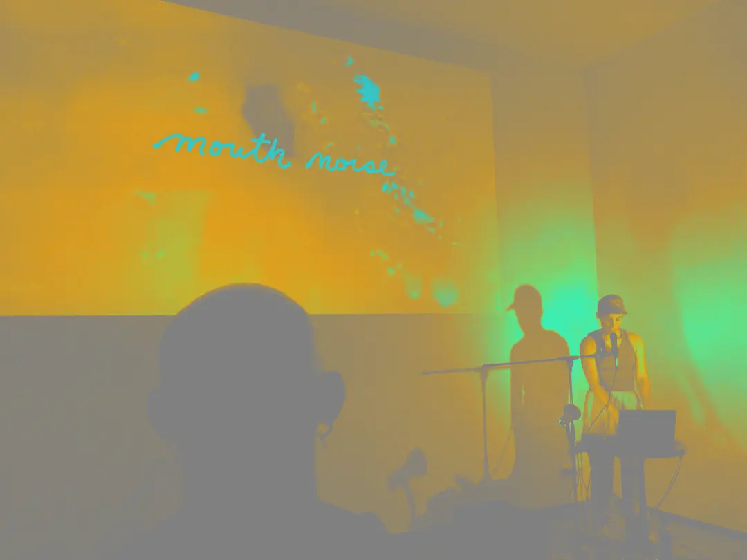 Nina sings from the courner while a video projected says Mouth Sounds