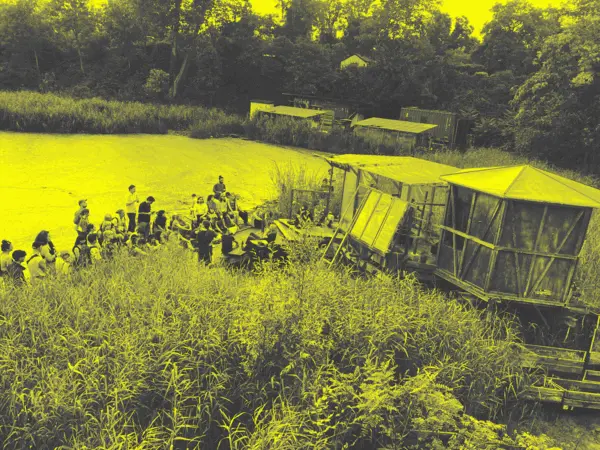 people sitting on a pier next to eco-buildings listening to experimental audio transmissions