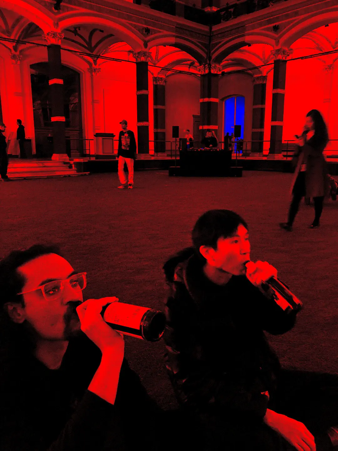 Yazzus DJs in large hall with two drinkers in foreground