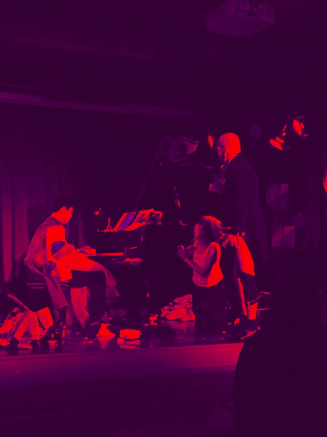a piano player surrounded by performance artists tormenting him