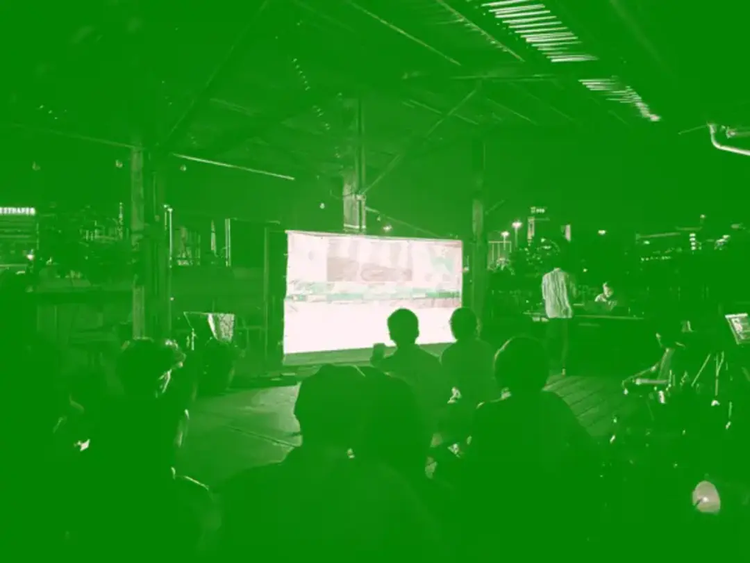 Folks watching visuals from SarahGHP projected on a construction barrier