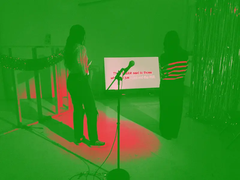 two women stand in front of an artwork by Mekko Harjo, viewing a story told in text standing in an homage to the club Bossa Nova Civic Club despite looking nothing like it
