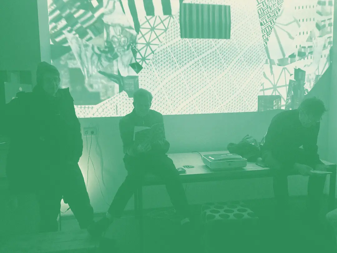 people hanging out on a desk in the studio with artwork projected behind
